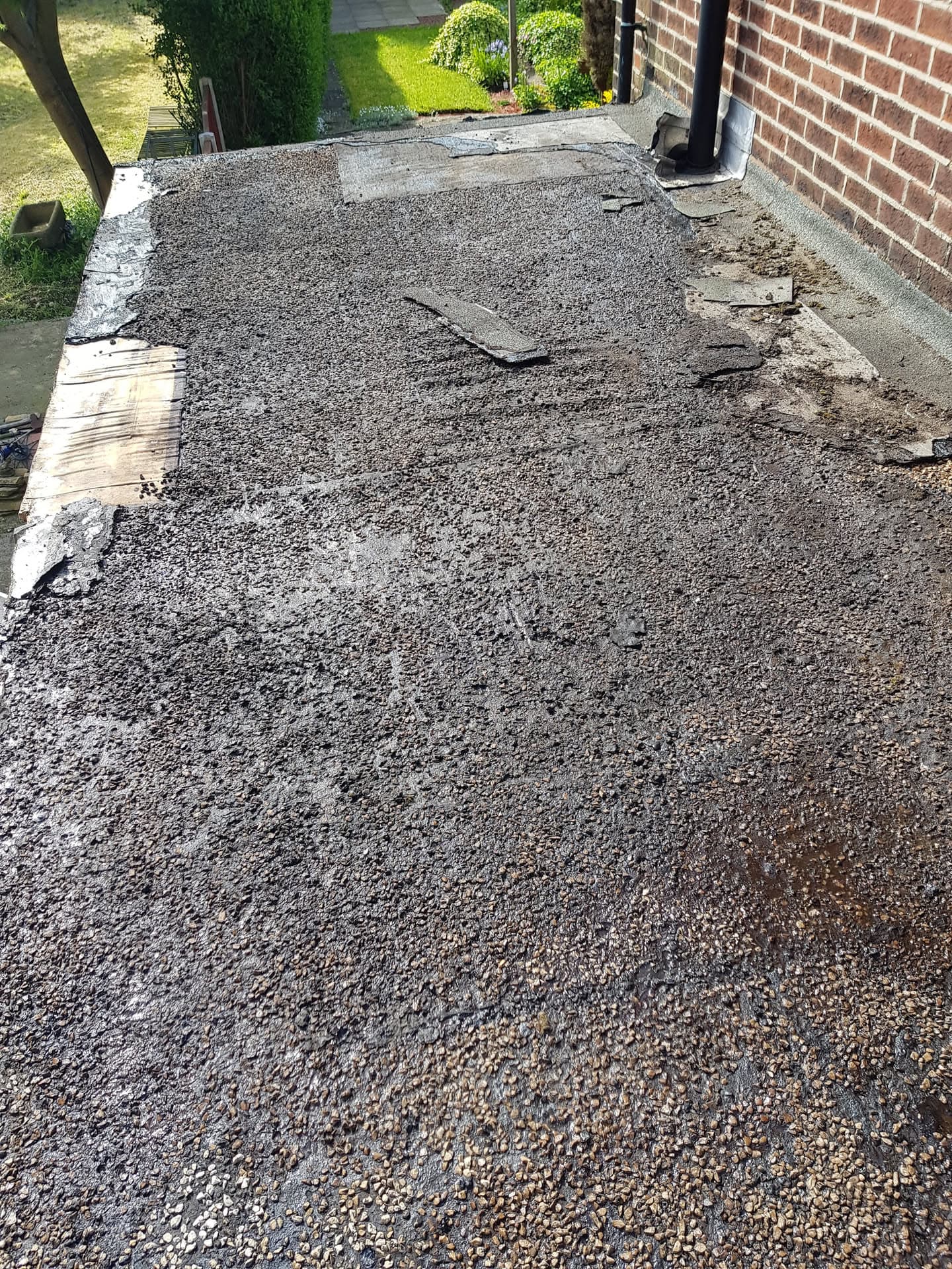 Flat roof with grey felt covering and stone chippings during installation