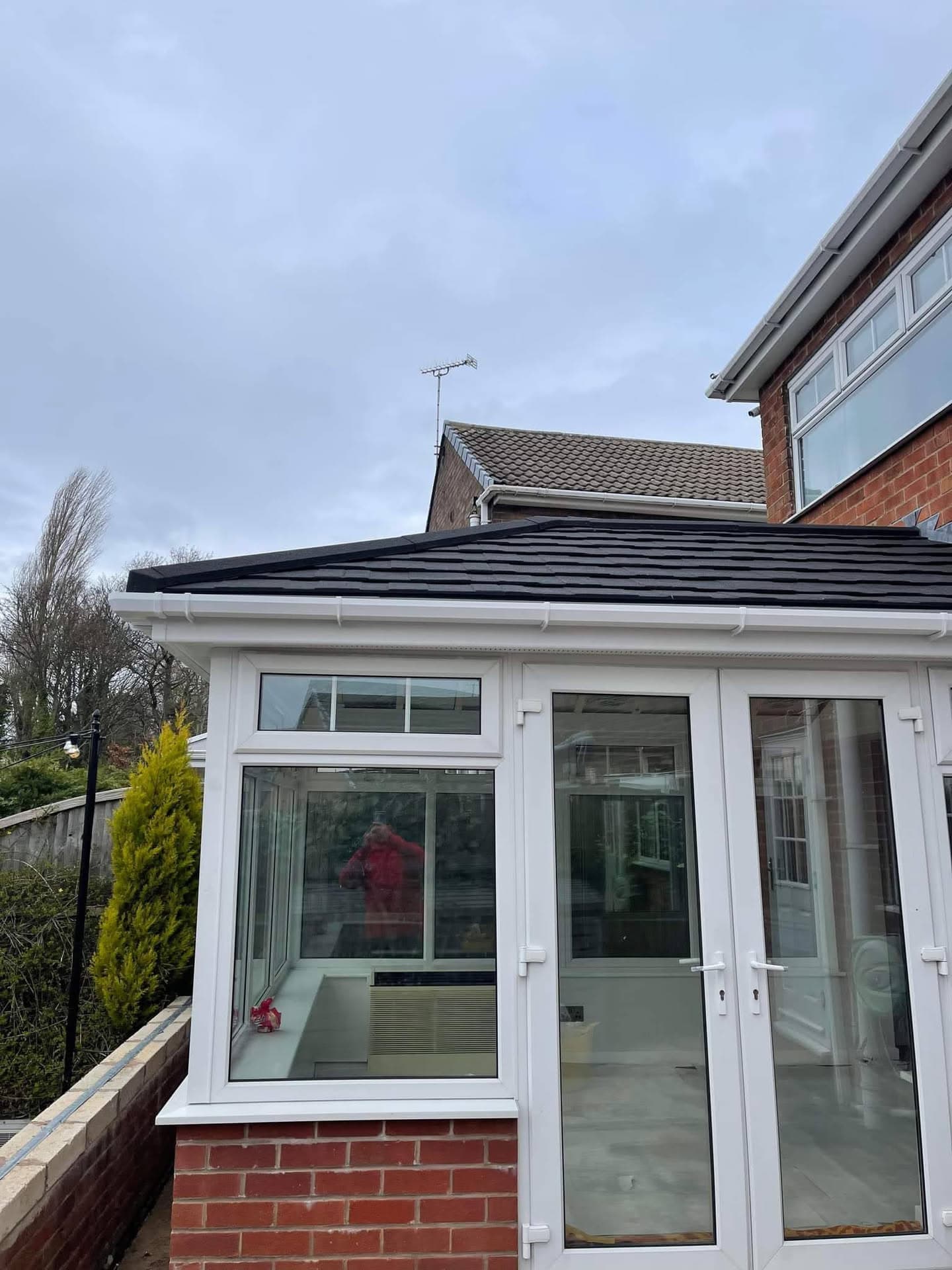 Conservatory with dark grey metal standing seam roof and white uPVC frames