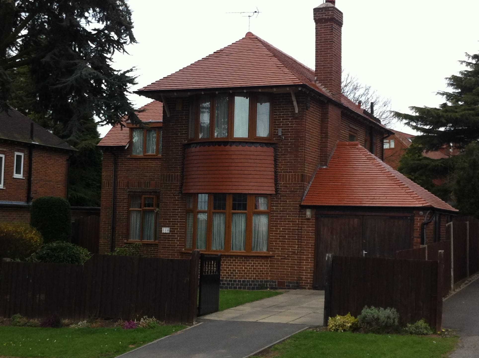 Red clay tiled pitched roof on brick house with chimney stack and attached garage