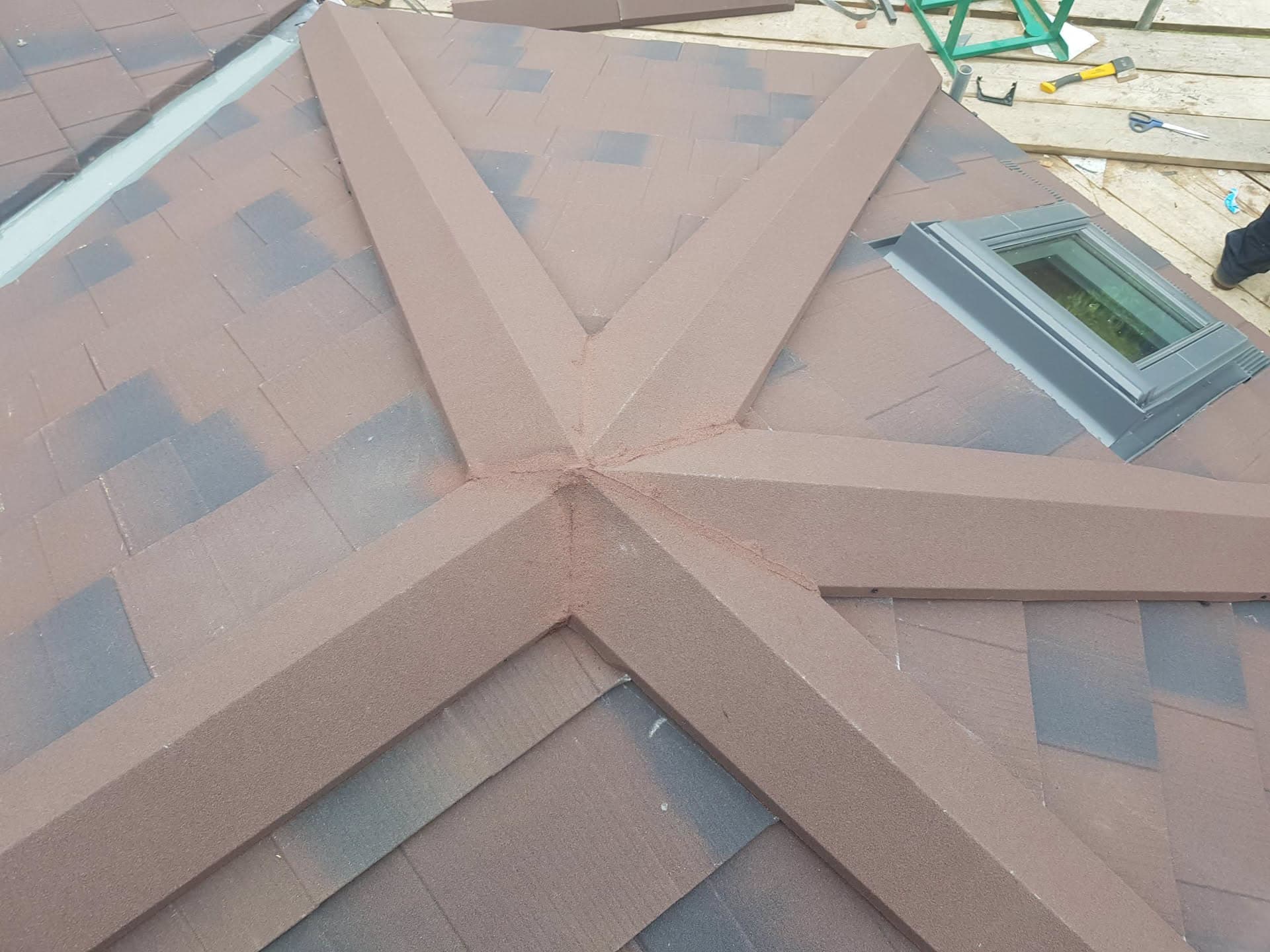 Pitched roof with brown concrete tiles and grey roof window during installation