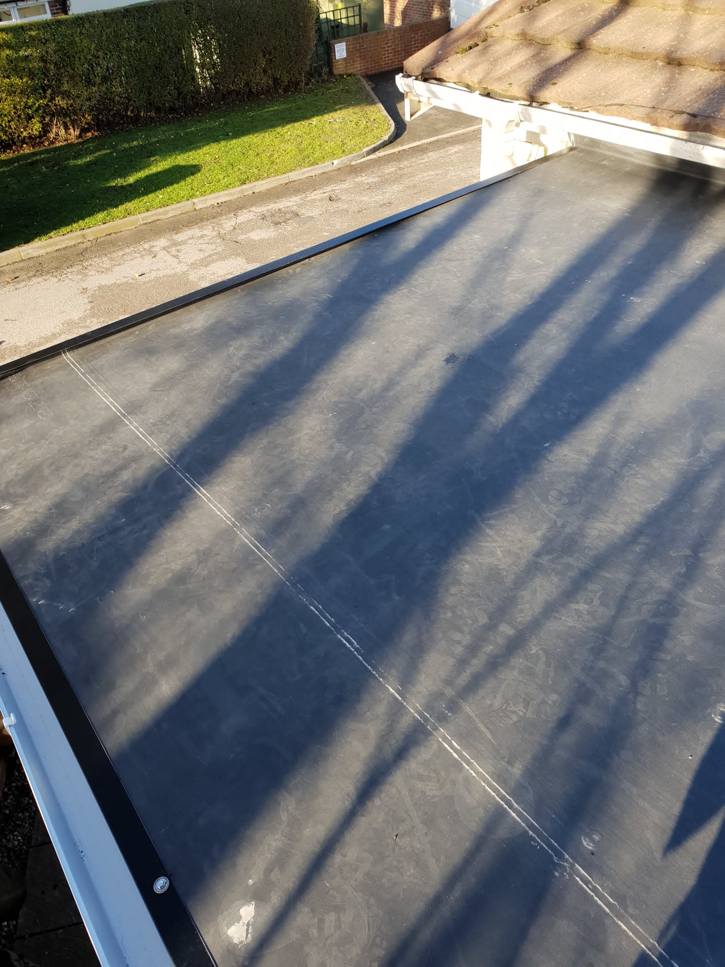 Flat roof with EPDM rubber membrane and white fascia trim on residential extension