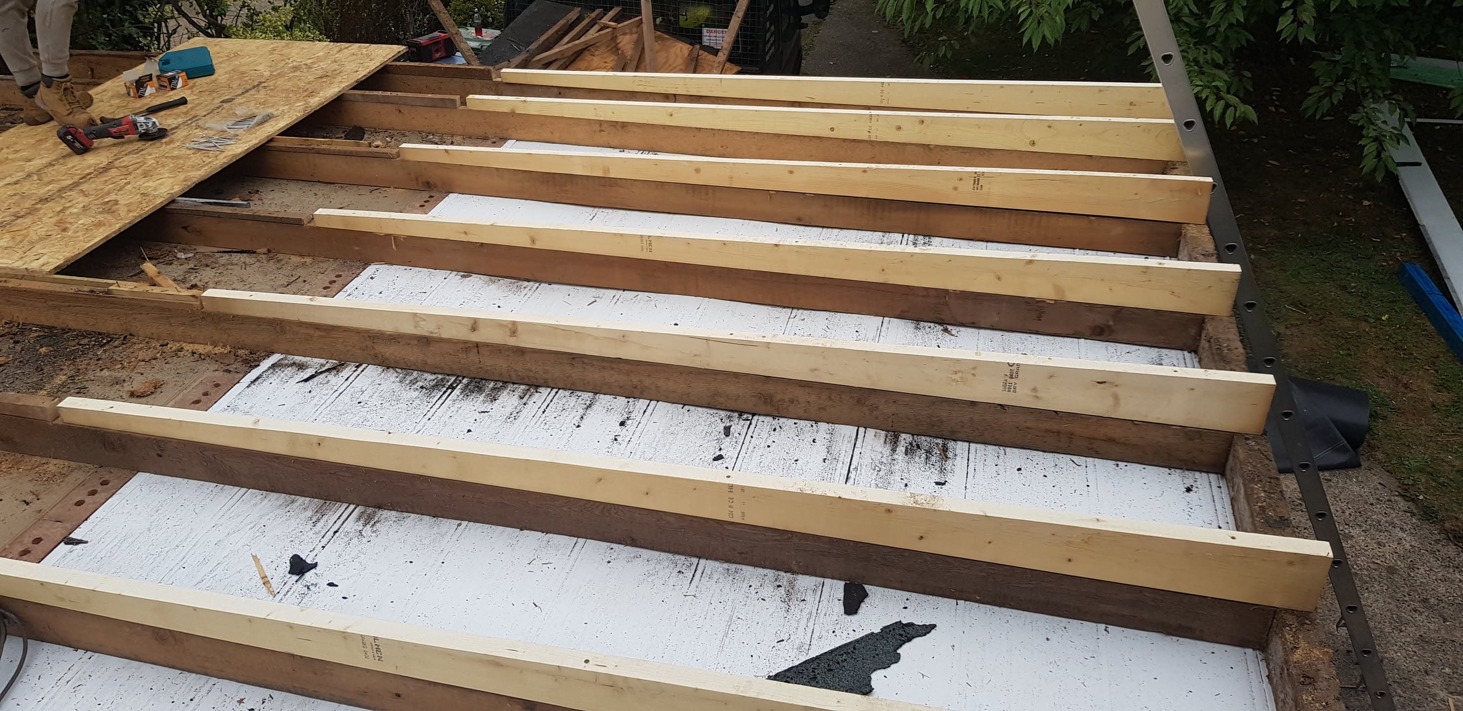 Flat roof construction with timber joists and white membrane underlay