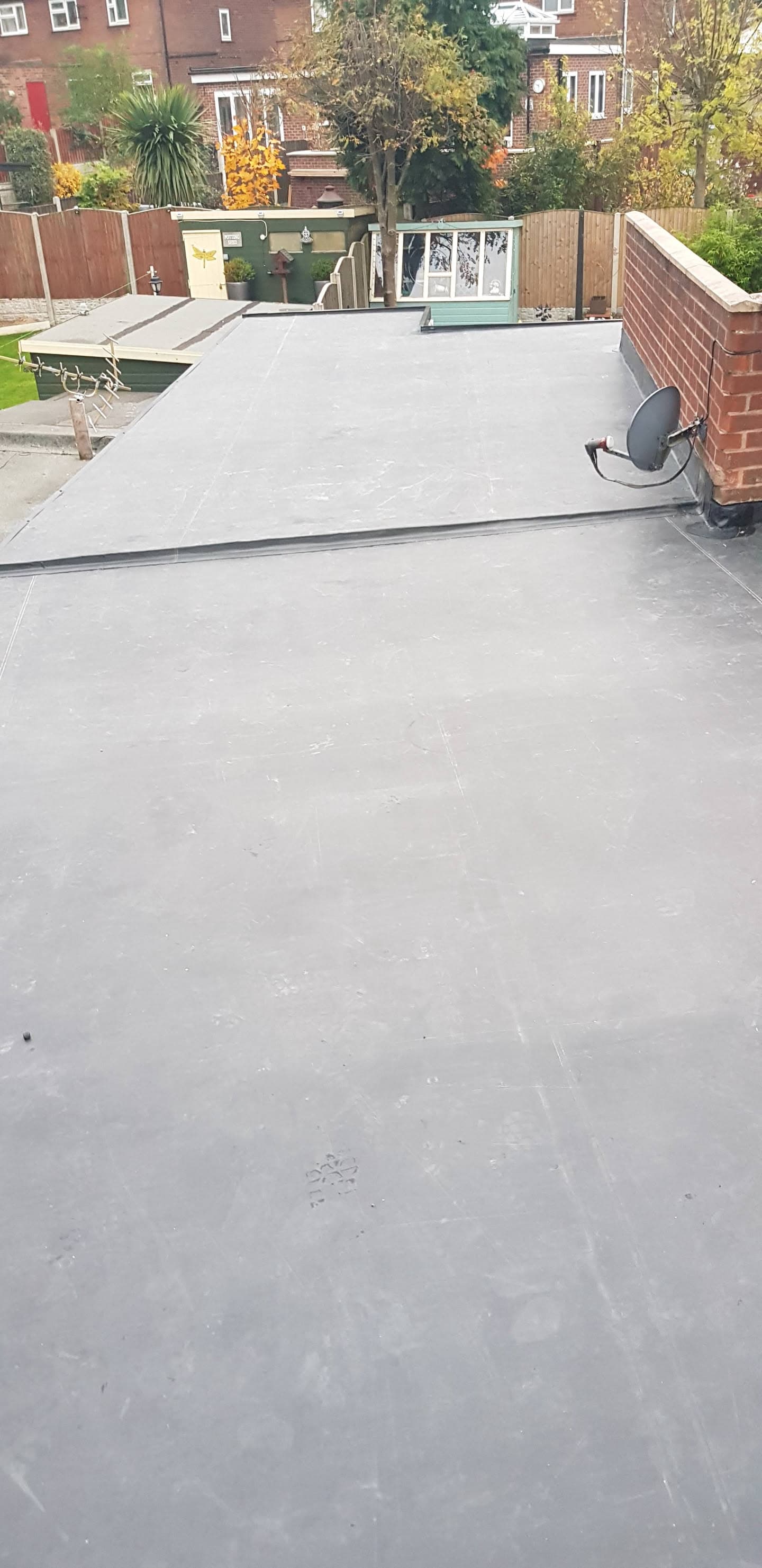 Completed grey EPDM rubber flat roof on residential extension with brick parapet walls