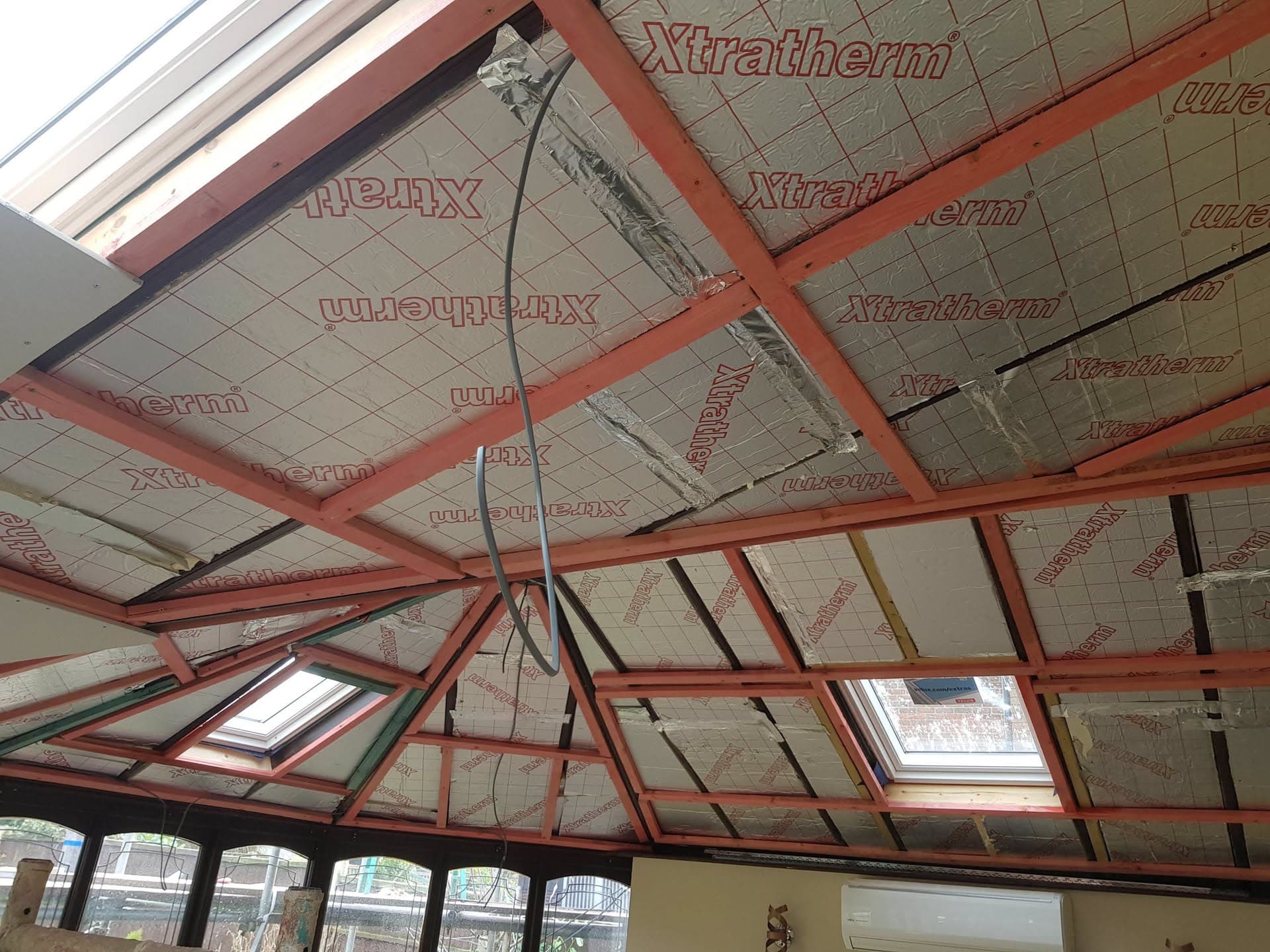 Conservatory roof interior showing red steel frame, insulation boards and roof windows during installation