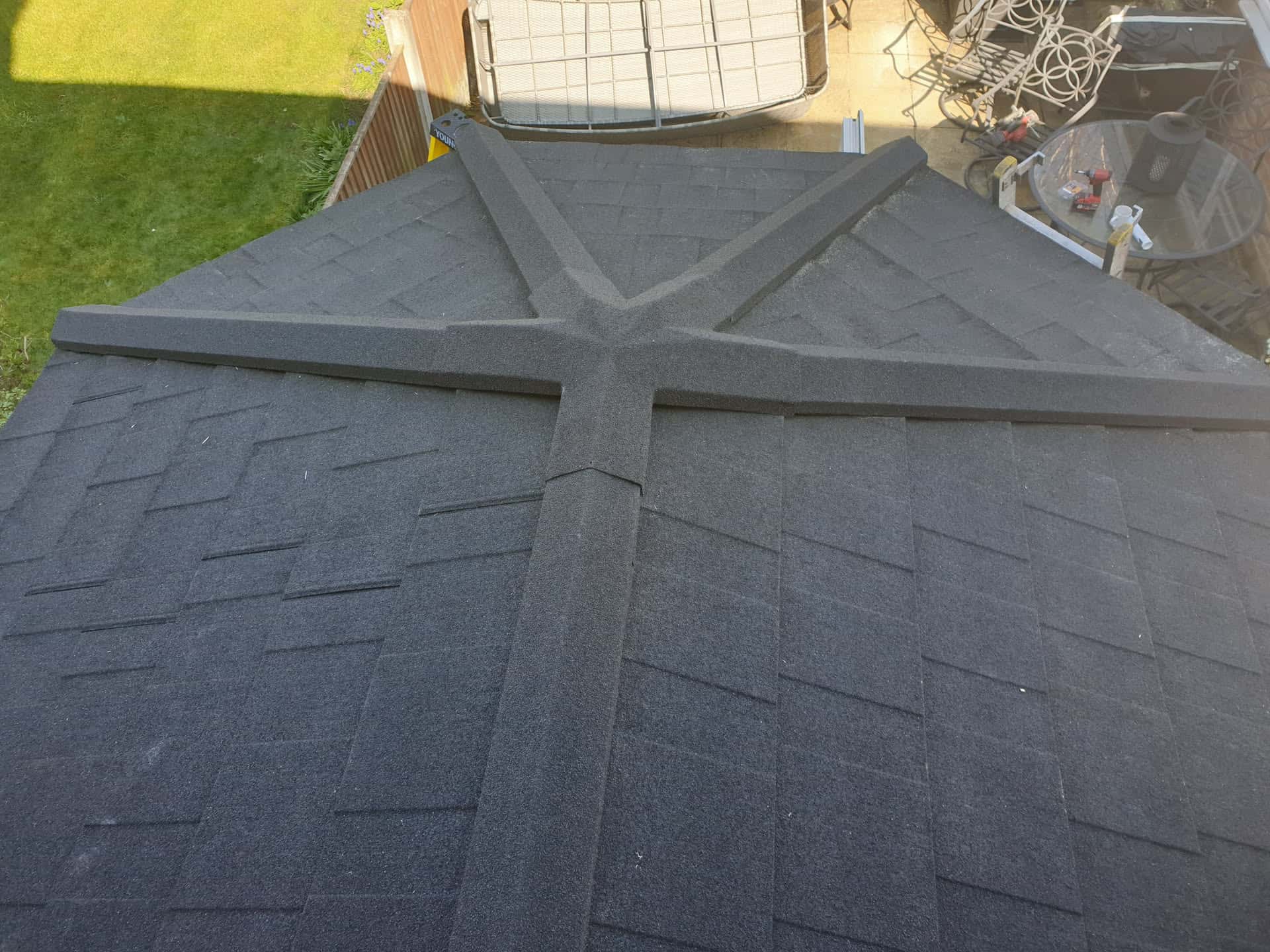 Completed conservatory roof with dark grey felt tiles and ridge capping viewed from above