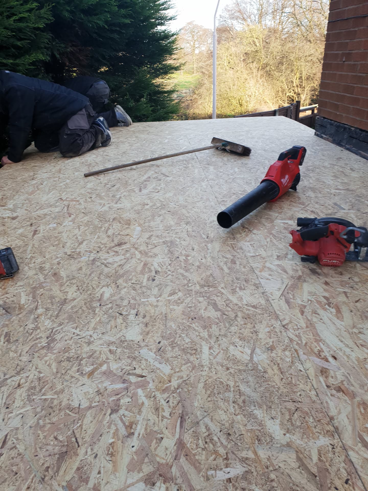 Fitter working on flat roof with OSB decking and power tools
