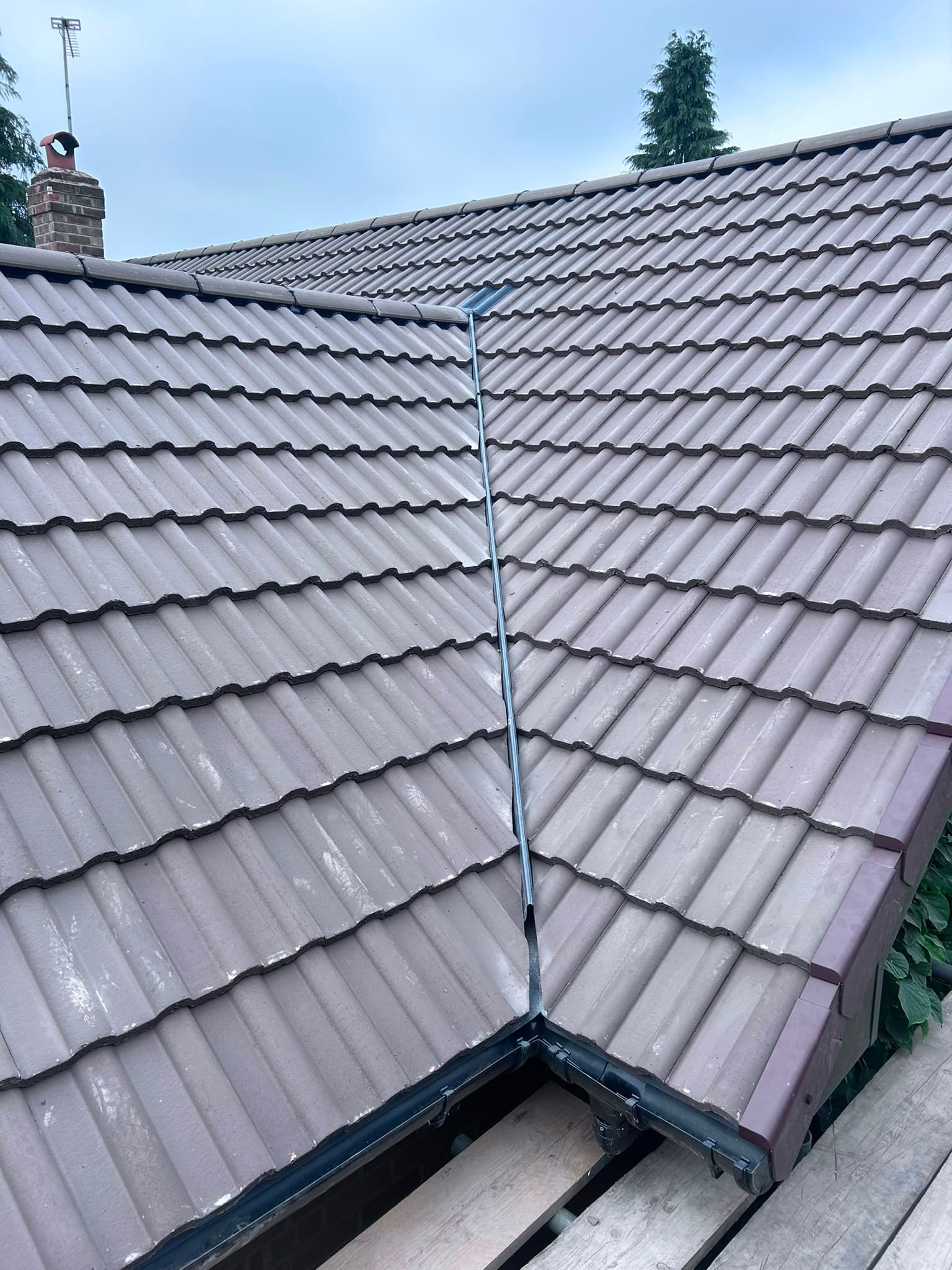 Newly completed concrete pantile roof with a fresh lead valley, dry verge and new guttering