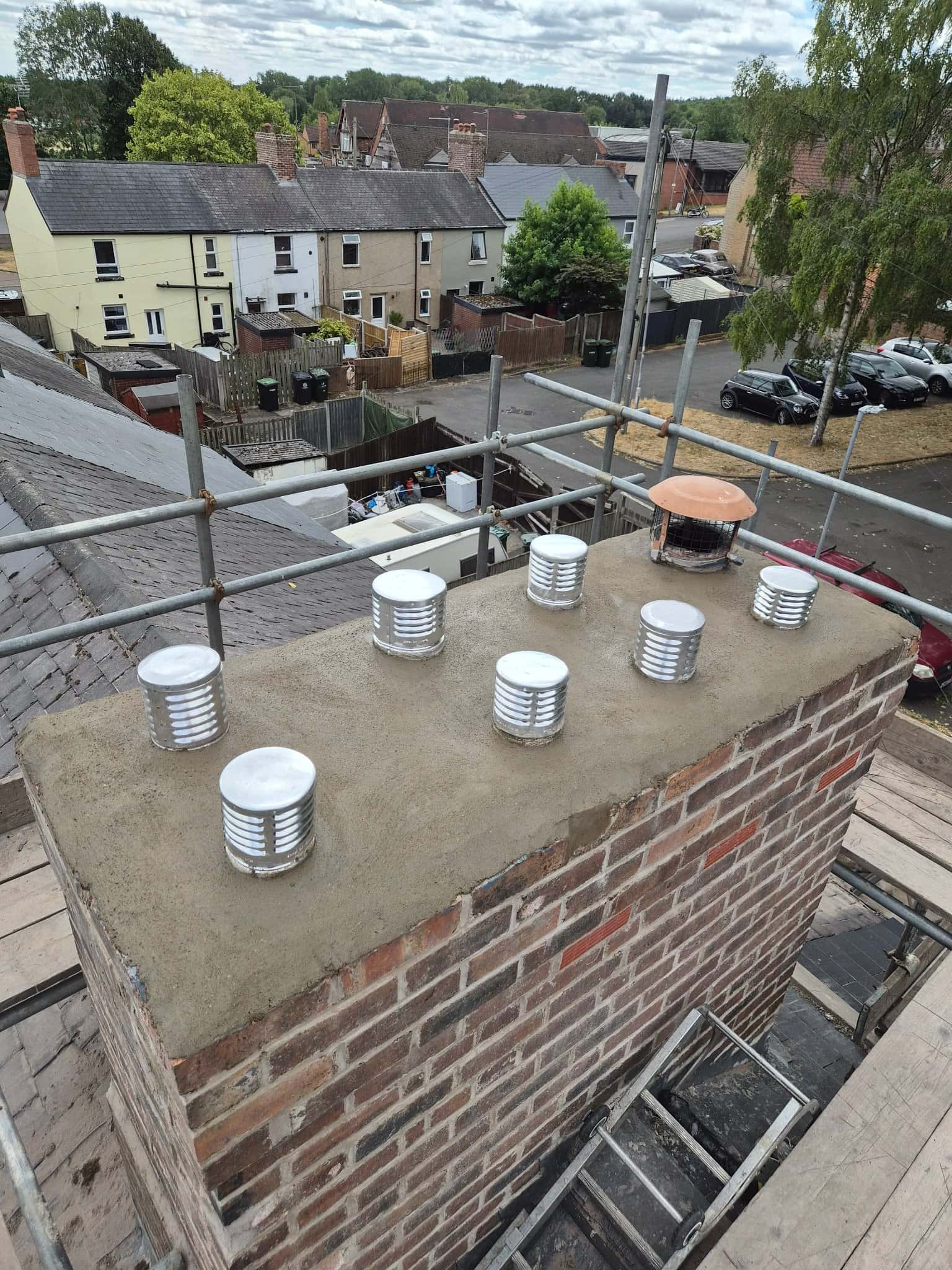 Restored brick chimney stack with fresh flaunching across the crown, new vent caps and repointed brickwork