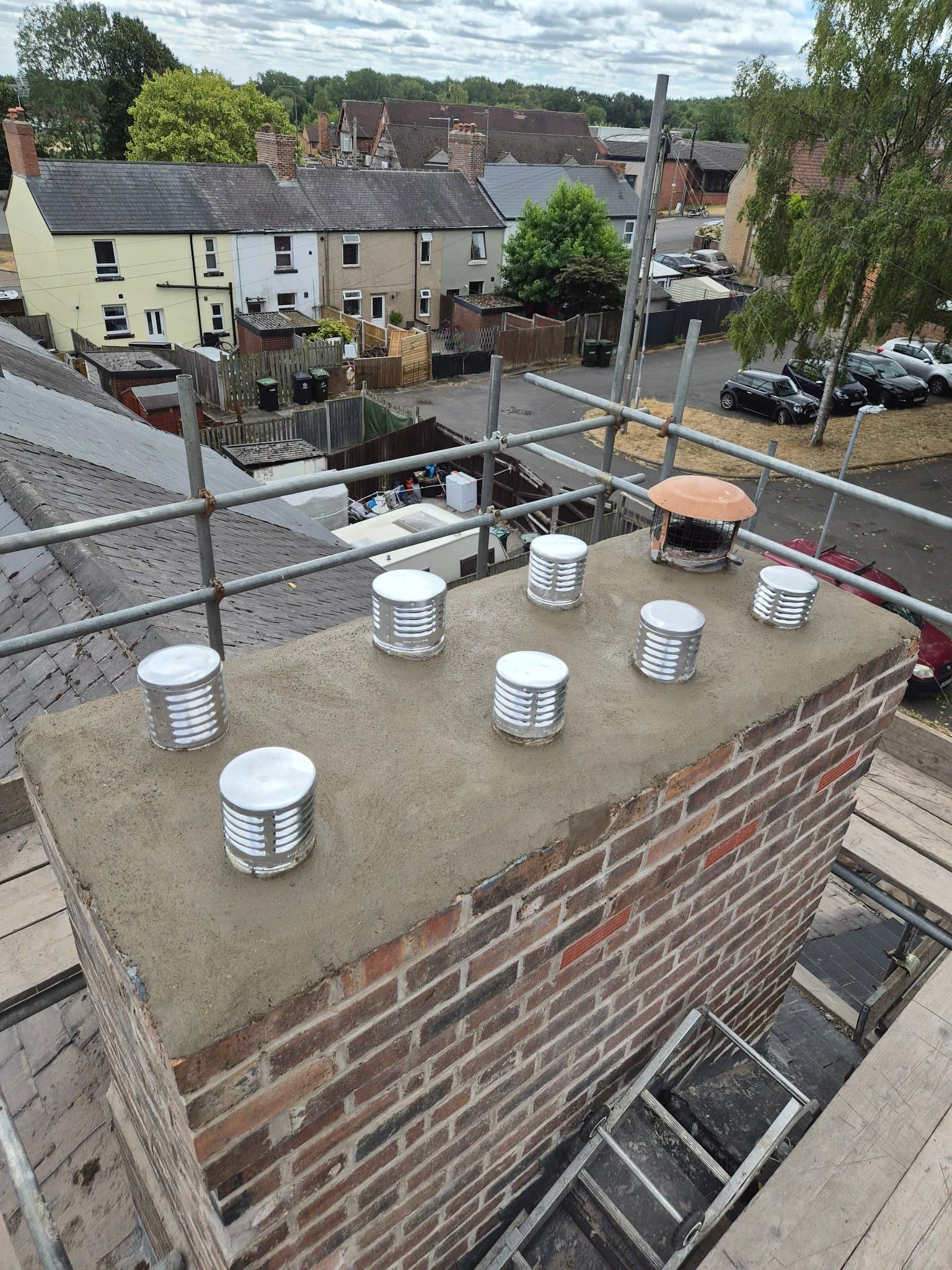 Restored brick chimney stack with fresh flaunching across the crown, new vent caps and repointed brickwork